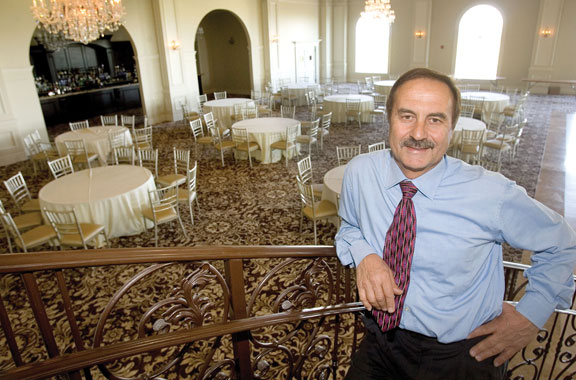 Joe Geloso Sr. stands on a staircase overlooking a grand ballroom at 