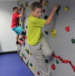 Naugatuck residents Derrick Jagello, 12, in front, and Tyler Demoura, 11, make their way across the traverse climbing wall in the newly redesigned youth room at the Naugatuck YMCA May 15. The YMCA has launched a new afterschool program, #Go2y, for middle school students. –ELIO GUGLIOTTI 