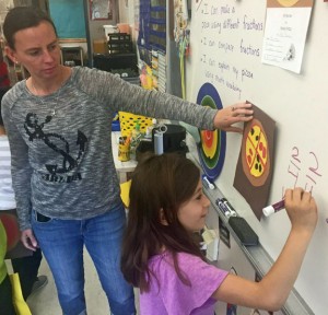 Maple Hill Elementary School teacher Jodie Burns watches as first-grader Ava Cabazas solves a math problem on the board last week. Naugatuck school officials are pleased with improved standardized test scores that they say are directly linked to changes in curriculum. –REPUBLICAN-AMERICAN